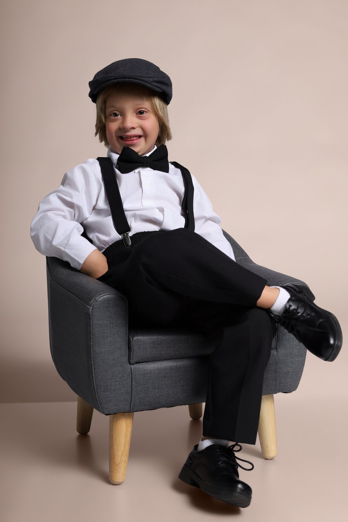 Wesley Wyatt smiling, seated in an armchair in suspenders and a newsboy cap