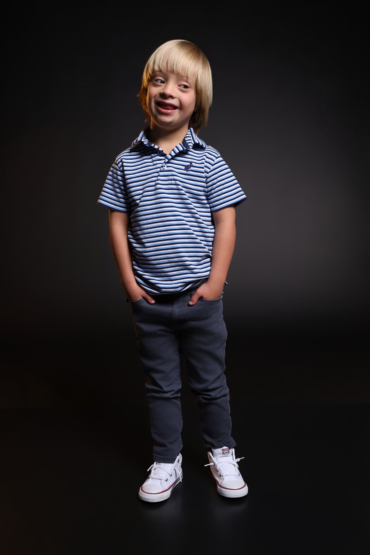 Wesley Wyatt standing with hands in pockets in a striped polo, smiling