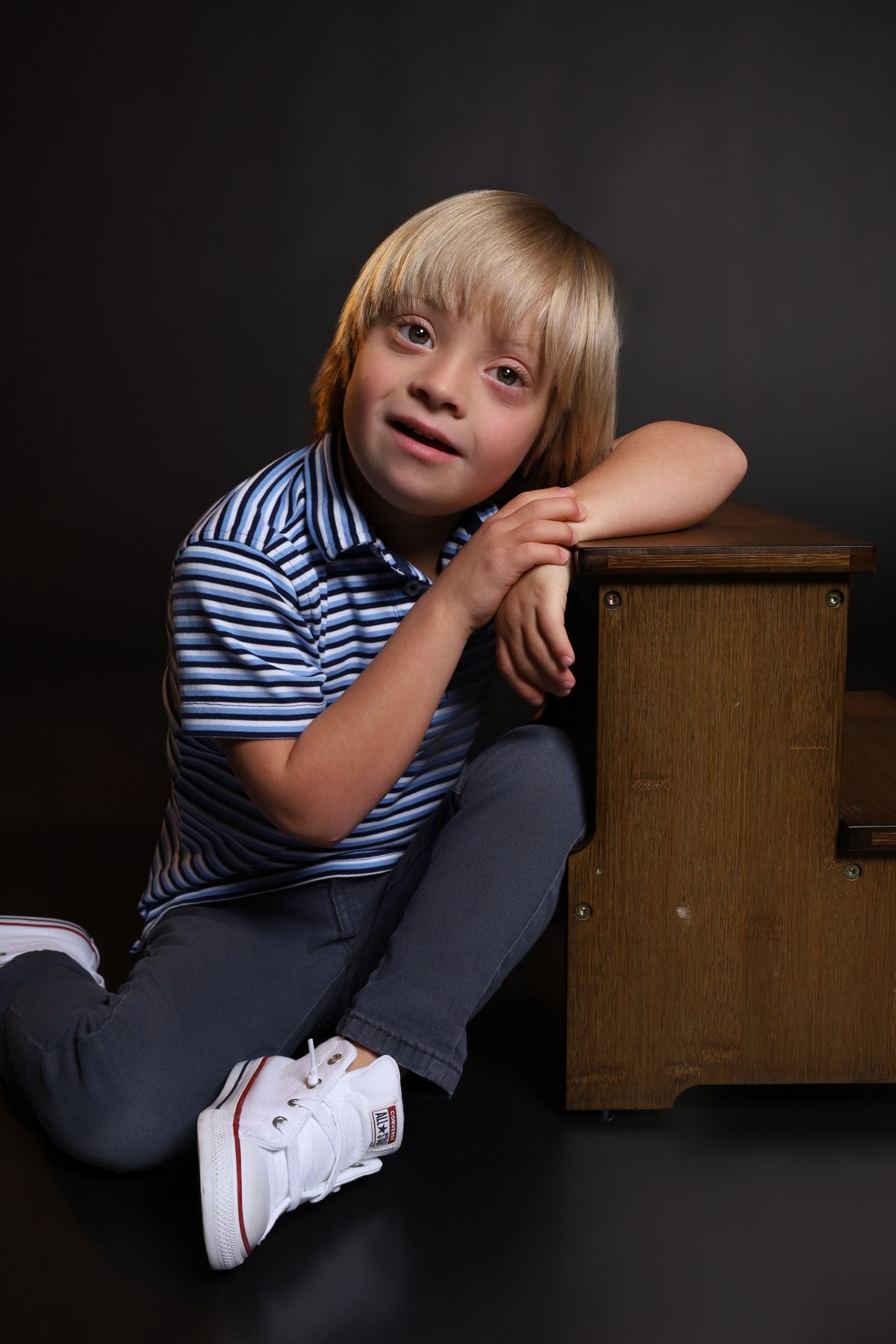 Wesley Wyatt seated on the studio floor, leaning on a wooden crate and smiling