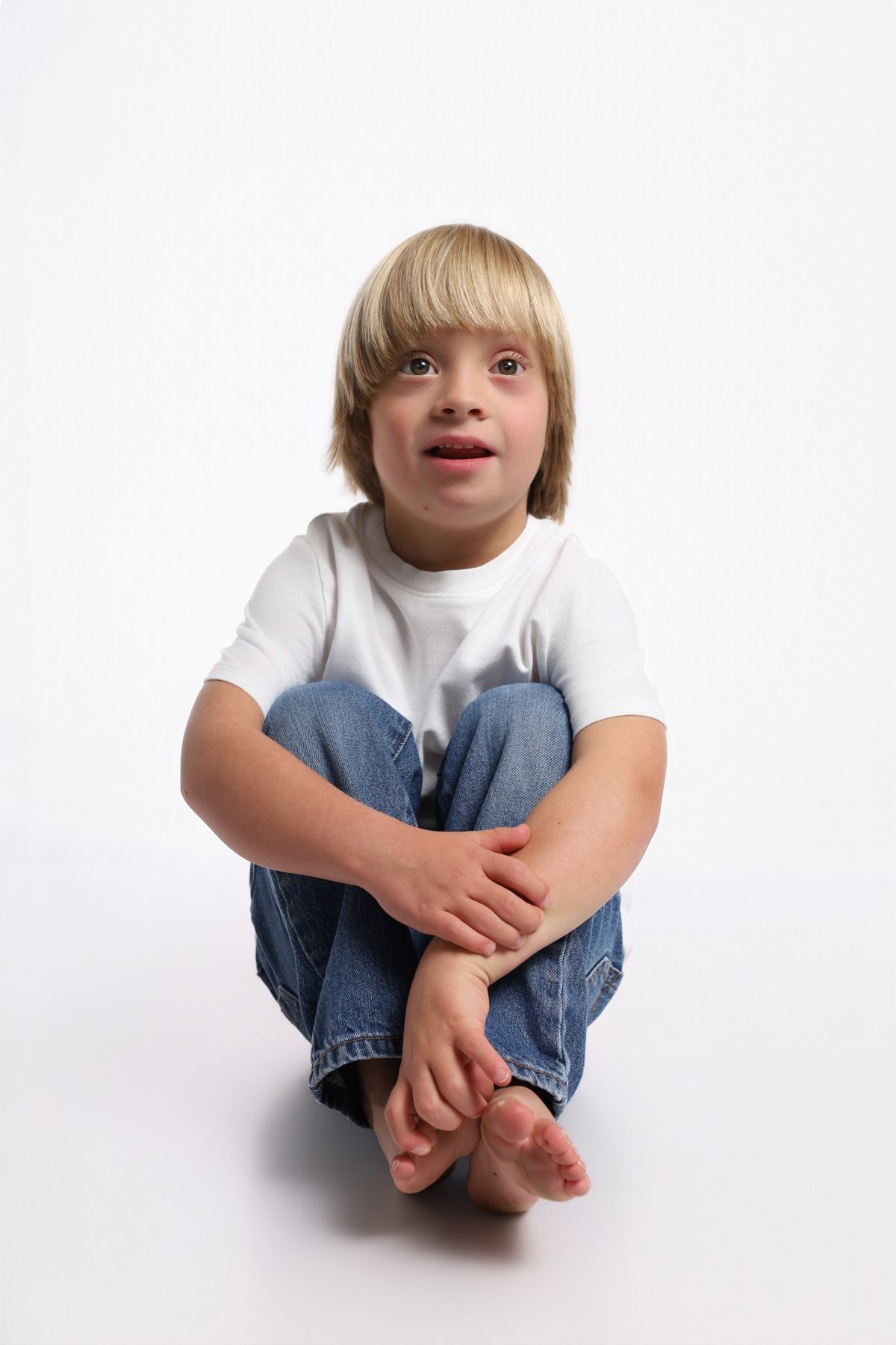 Wesley Wyatt in a white tee and jeans, seated hugging his knees