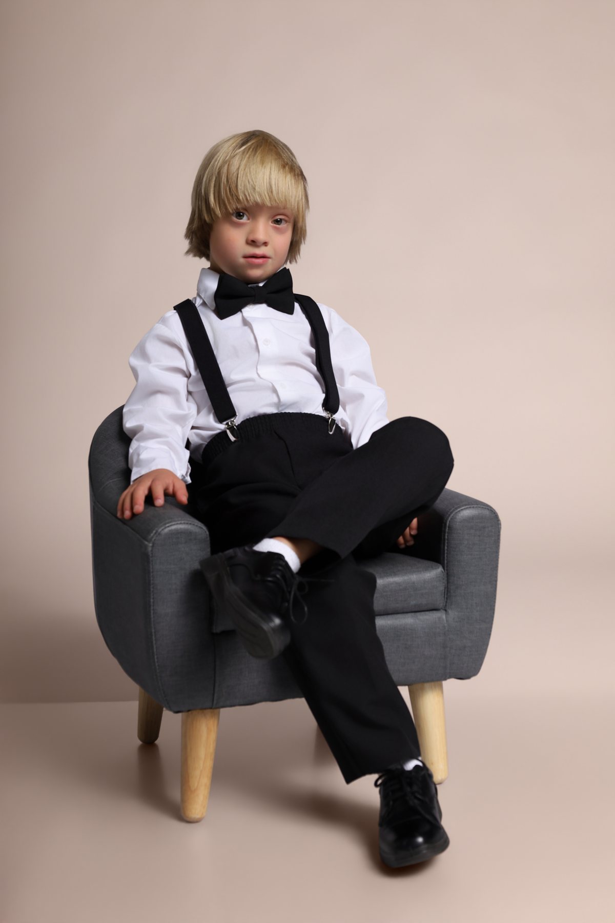 Wesley Wyatt seated with legs crossed in a bow tie and suspenders