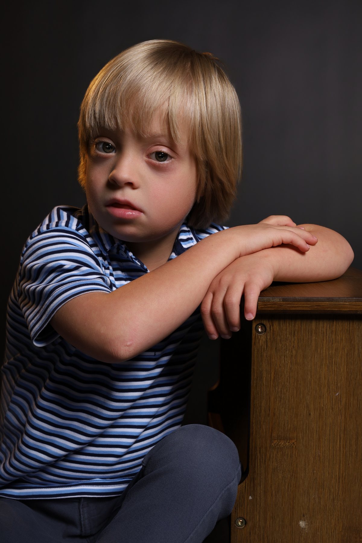 Wesley Wyatt leaning on a wooden crate in a striped polo, editorial look