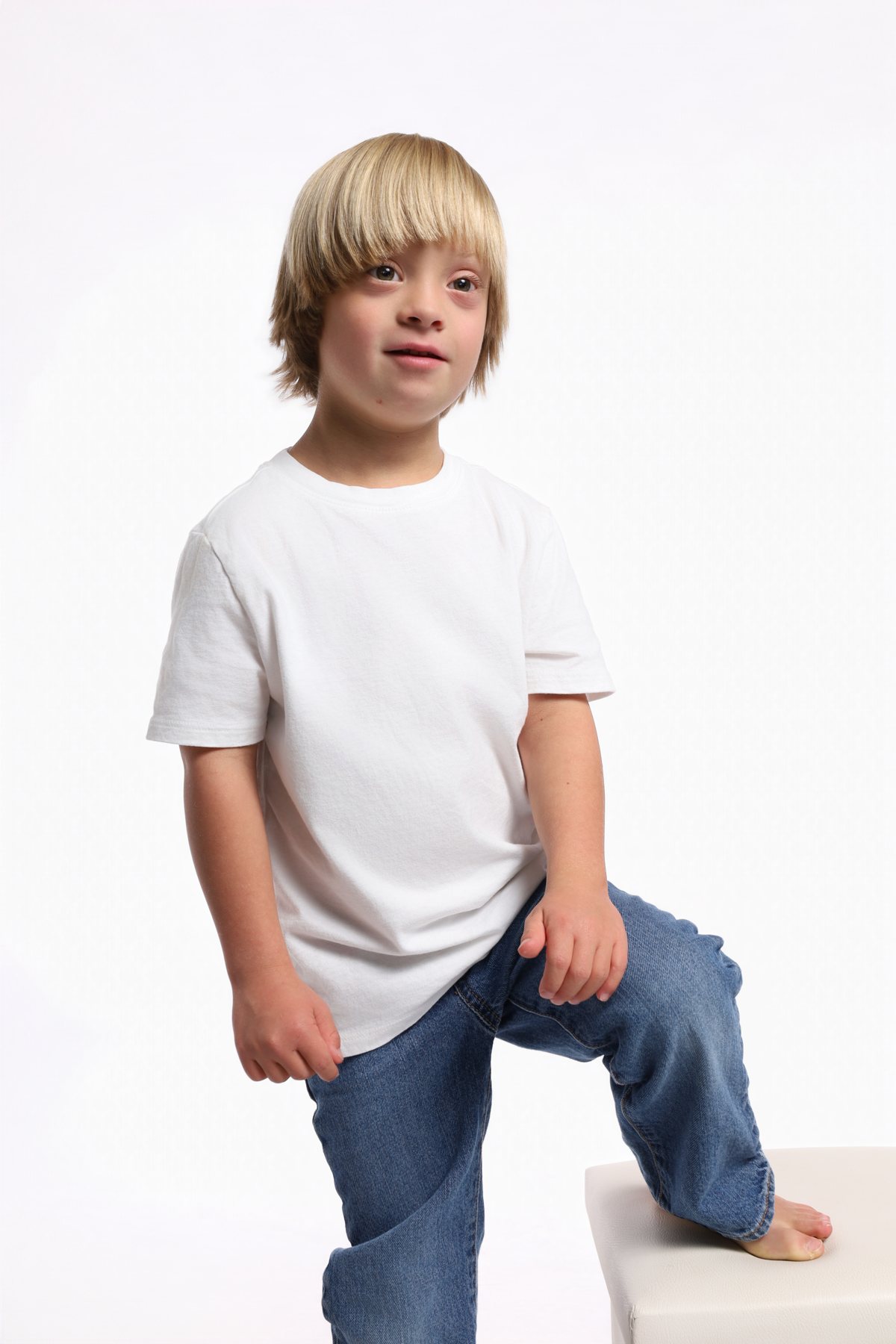 Wesley Wyatt in a white tee and jeans with one knee up on a posing block
