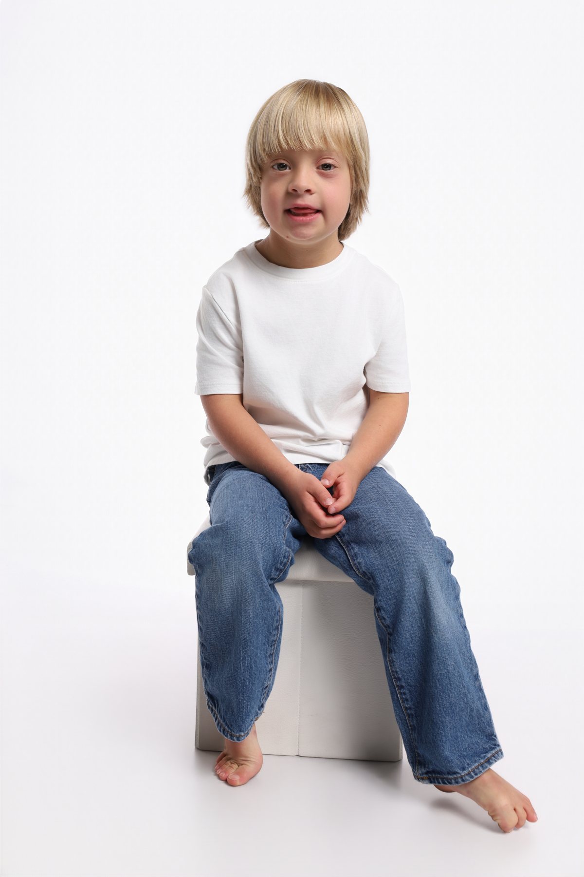 Wesley Wyatt seated on a white cube in a white tee and jeans